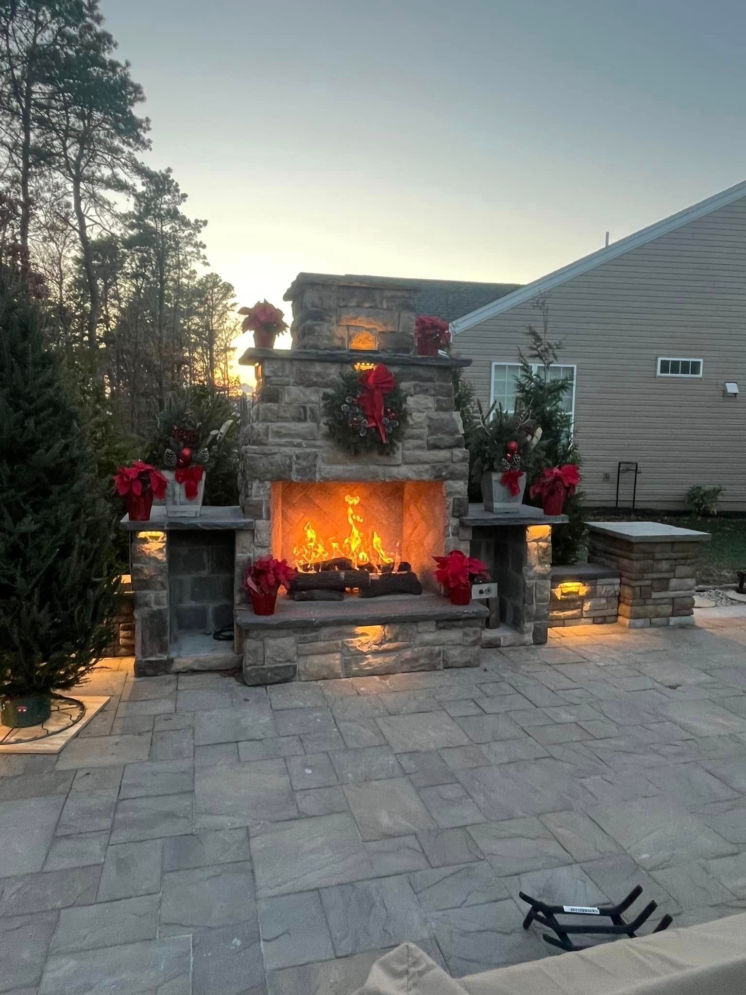 There is a fireplace in the backyard decorated for christmas.