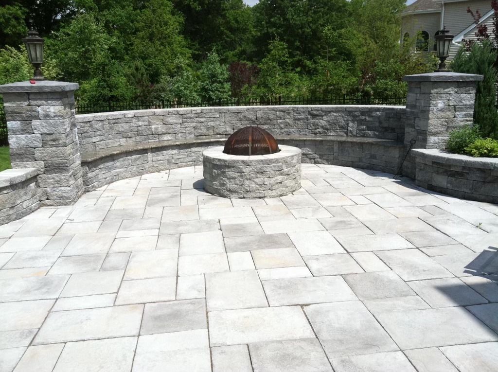 A stone patio with a fire pit in the middle