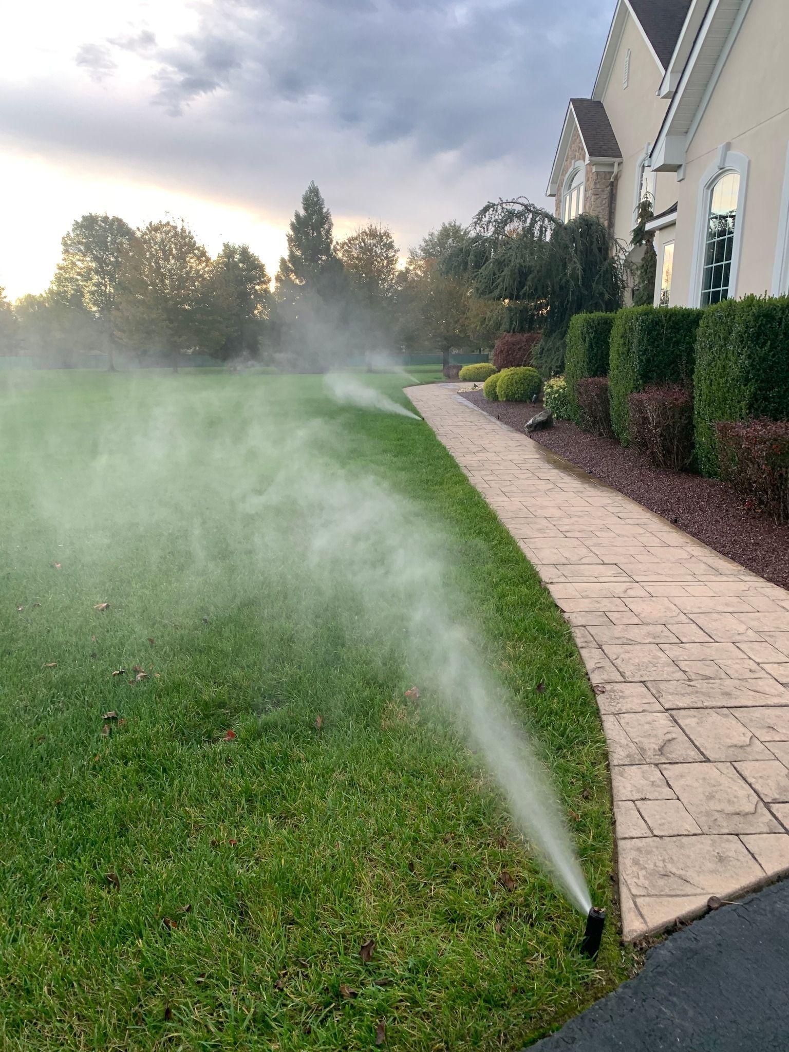 A lawn sprinkler is spraying water on a lush green lawn.