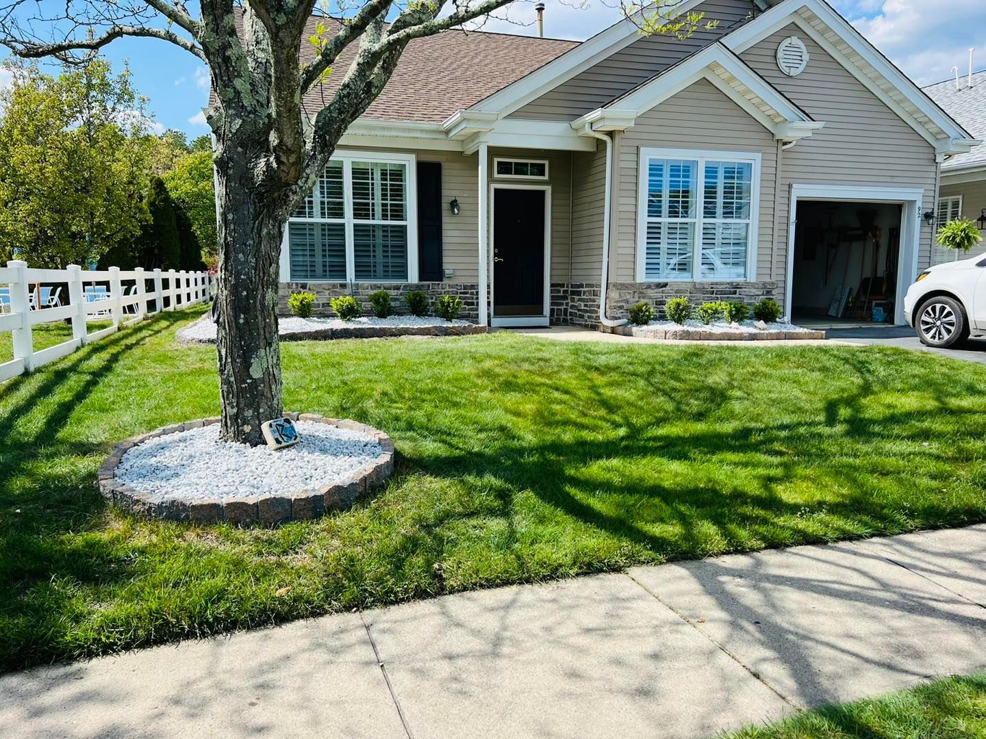 A house with a lush green lawn and a white car parked in front of it.