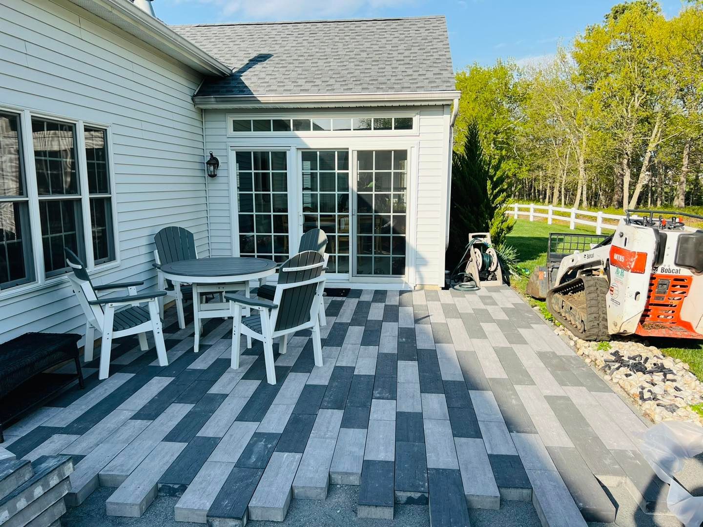 A patio with a table and chairs is being built in front of a house.