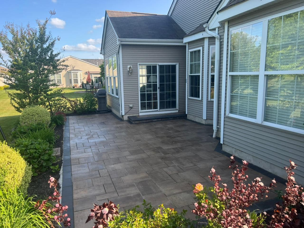A house with a patio in front of it and a sliding glass door.