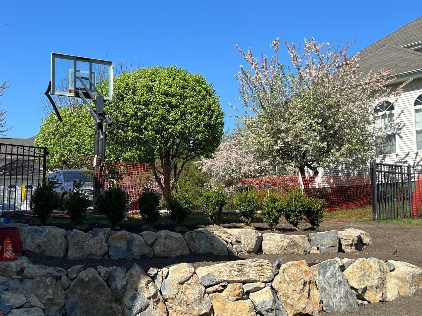 A basketball hoop is sitting on top of a rock wall in front of a house.