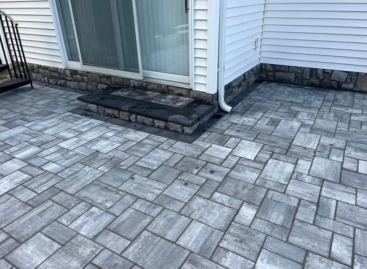 A brick patio in front of a house with a sliding glass door.