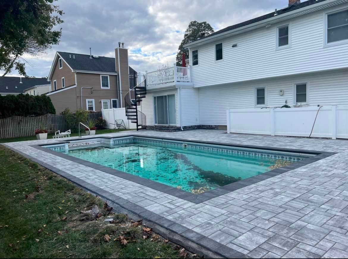 A large swimming pool is in the backyard of a house.