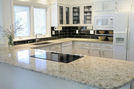White kitchen with granite countertops, black backsplash, and built-in microwave and fridge.
