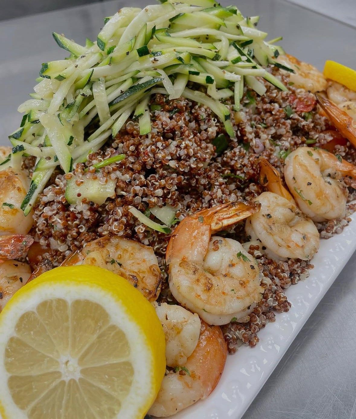 Grilled shrimp and quinoa salad with zucchini ribbons, lemon slices.