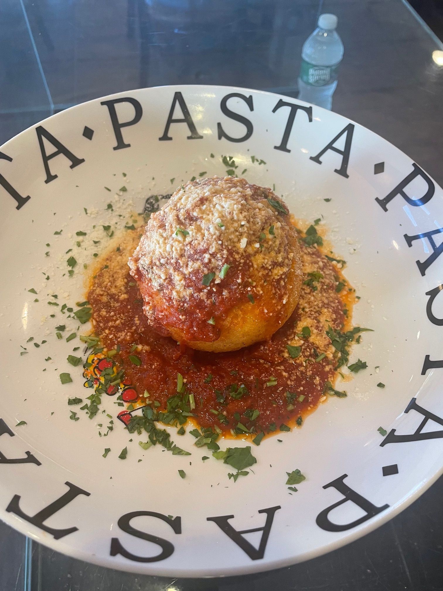 A white pasta plate with a meatball on it