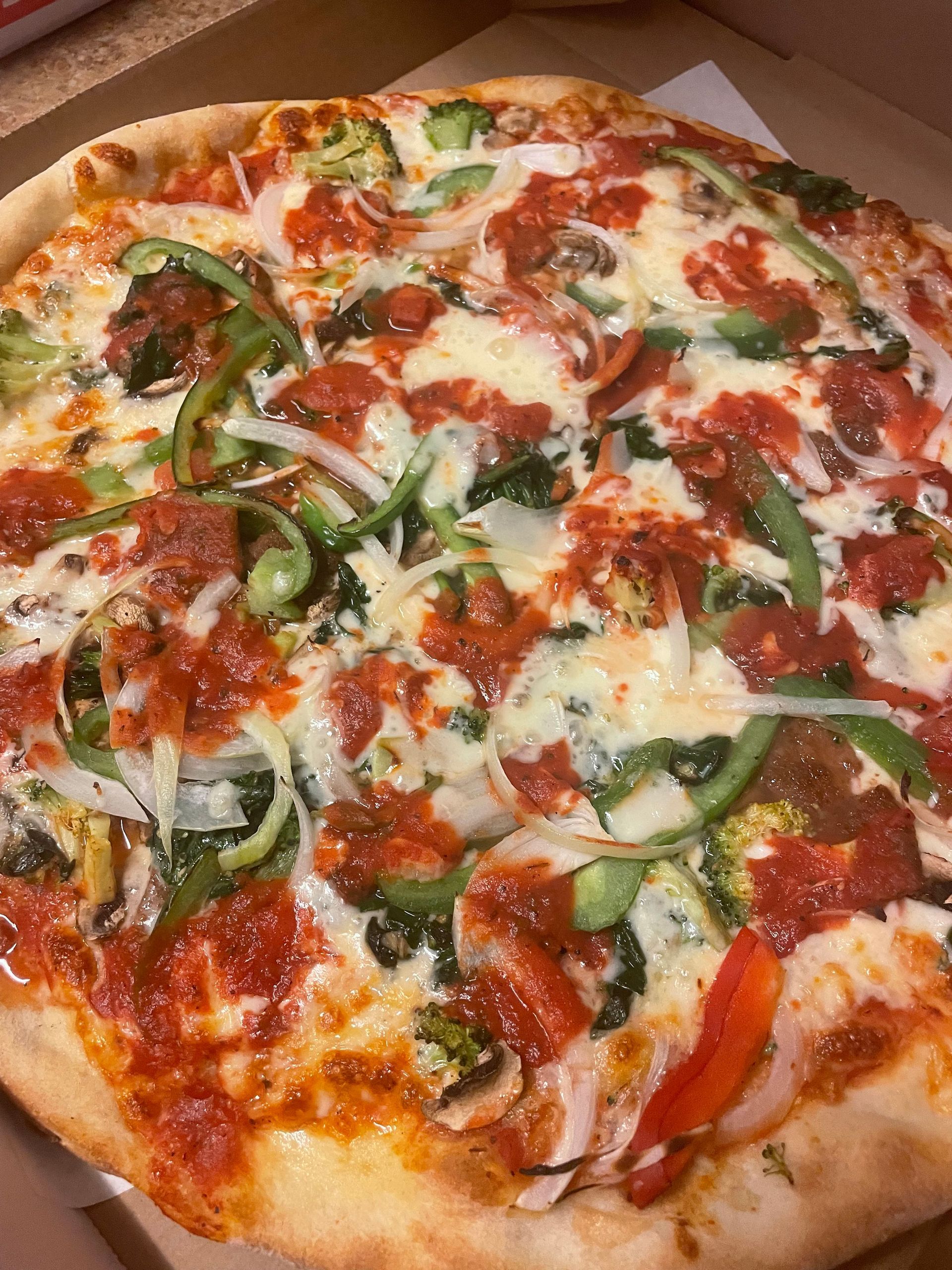 A pizza with a lot of toppings on it is in a box.