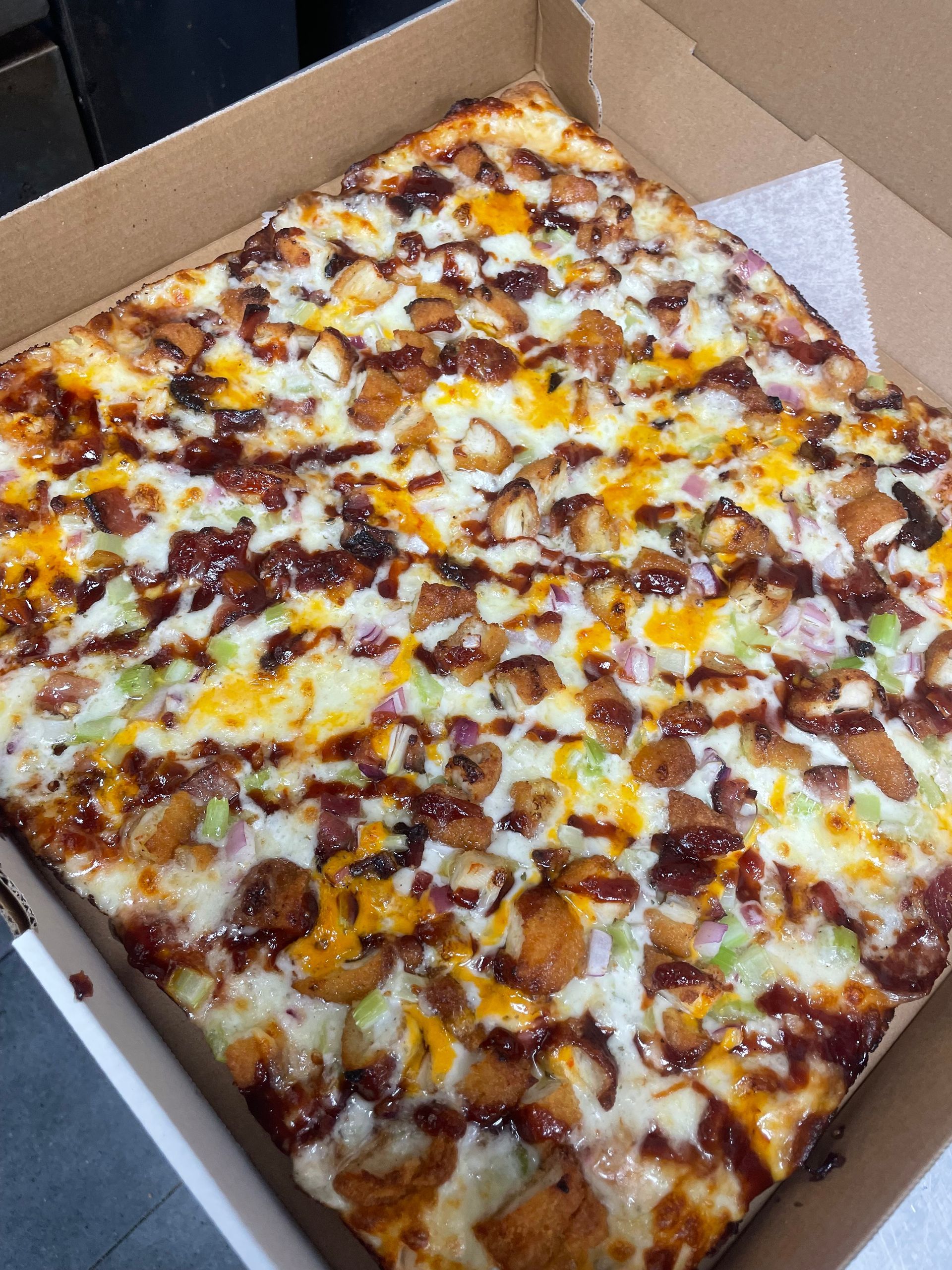 A pizza with a lot of toppings is in a cardboard box.