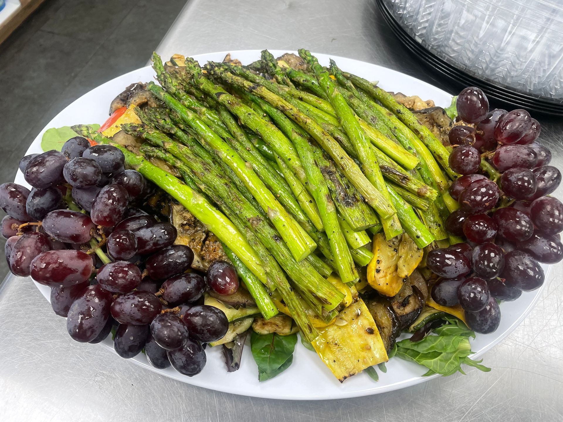 A plate of food with asparagus, grapes, and mushrooms on a table.