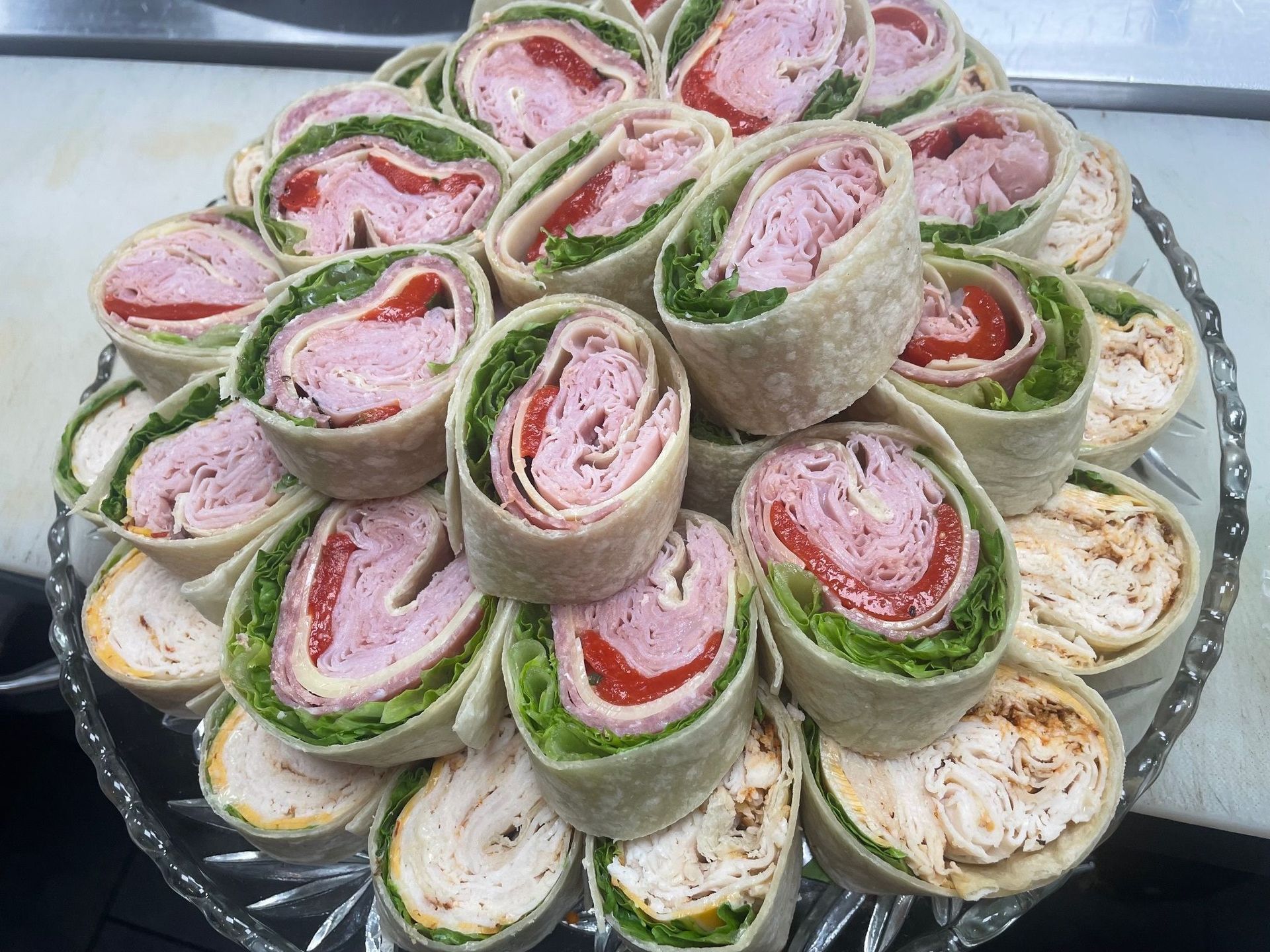 A glass plate topped with a variety of wraps and sandwiches.
