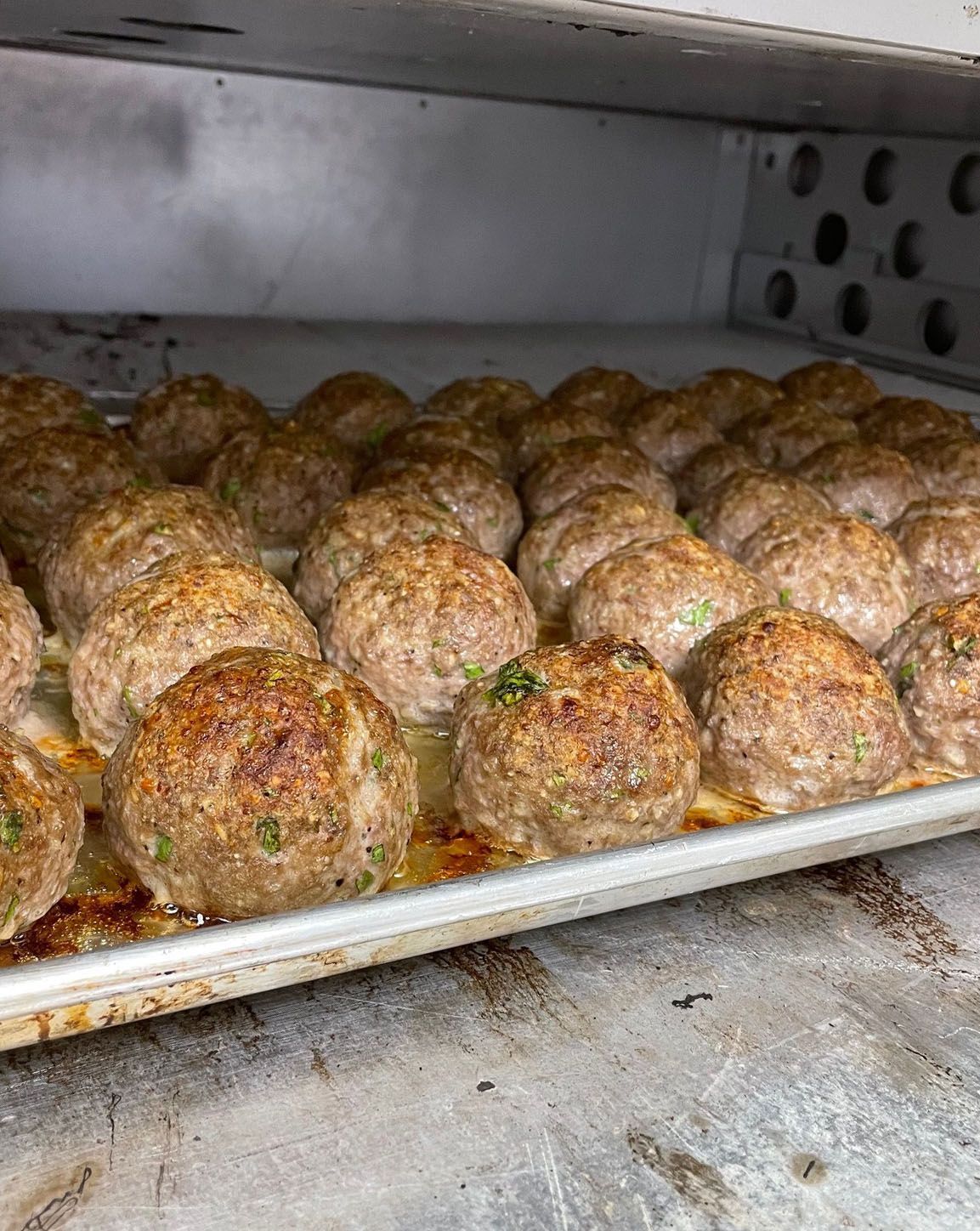 A tray of meatballs is sitting in an oven.