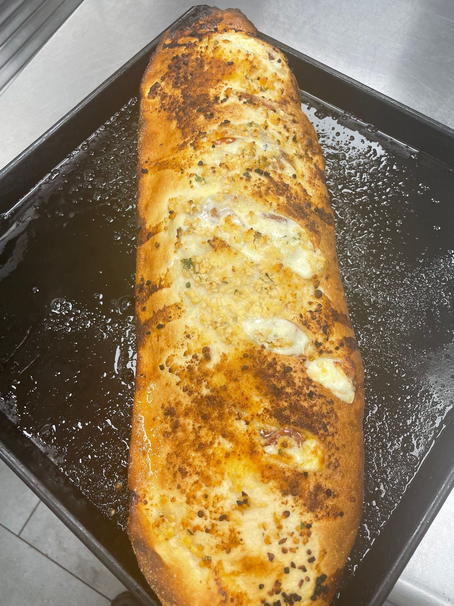 A long loaf of garlic bread is sitting on a pan