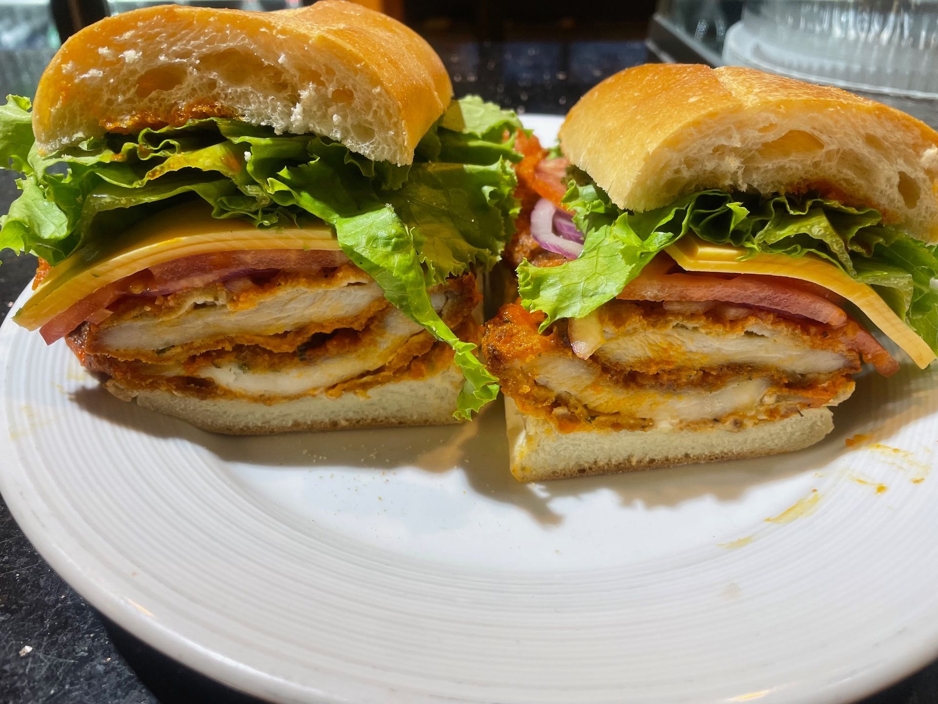 Two sandwiches are cut in half on a white plate.