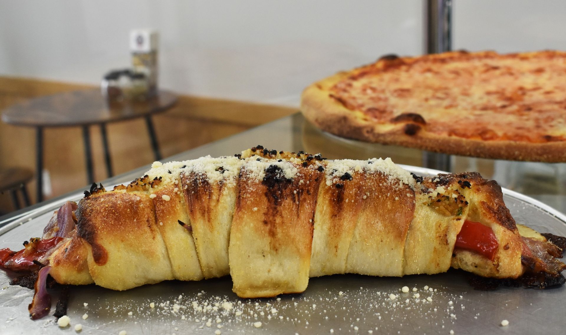 A pizza is sitting on a table next to a bread roll.