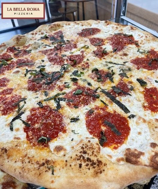 A pizza from la bella roma pizzeria is sitting on a table