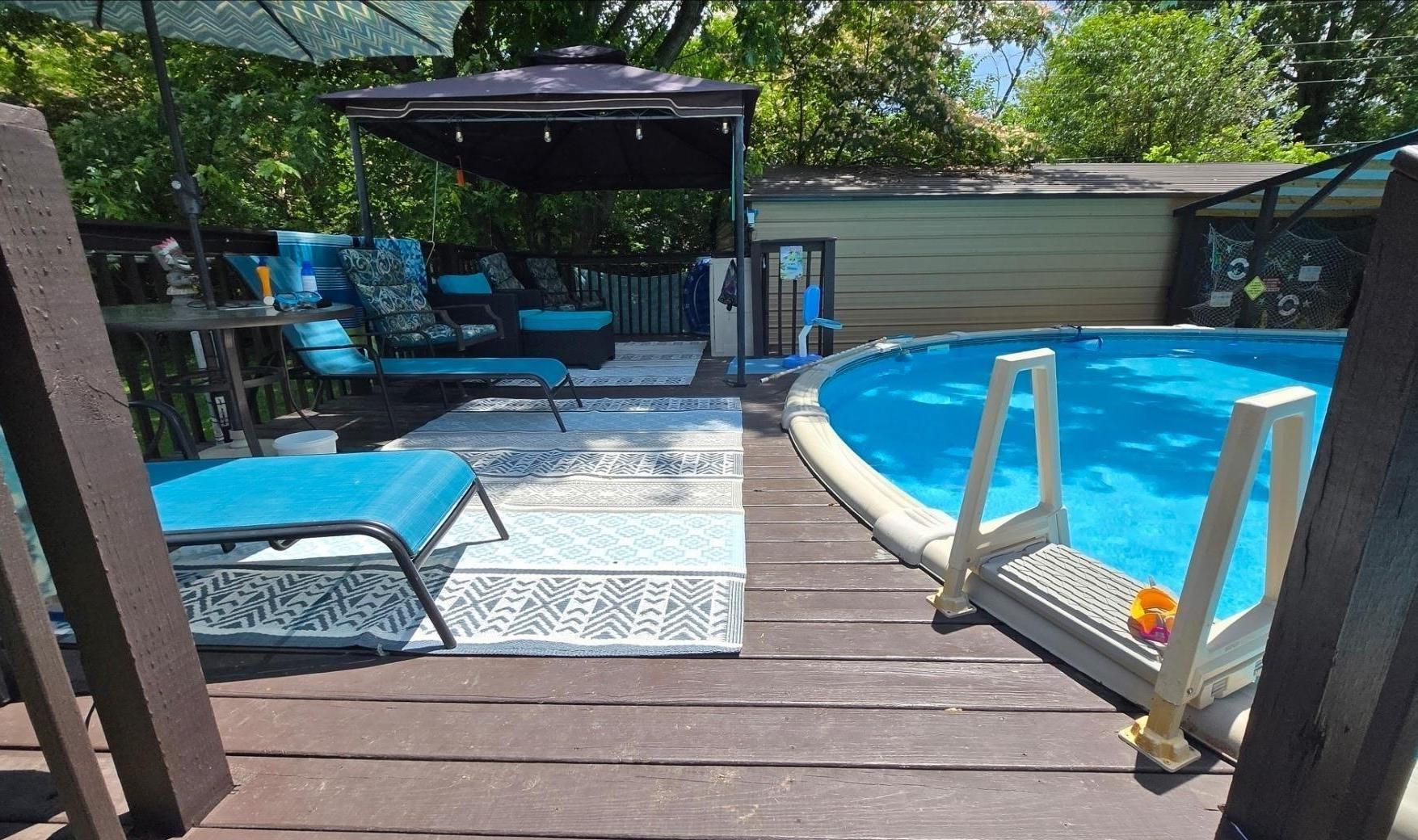 Backyard deck with blue lounge chairs, a shaded seating area, and a swimming pool on the right