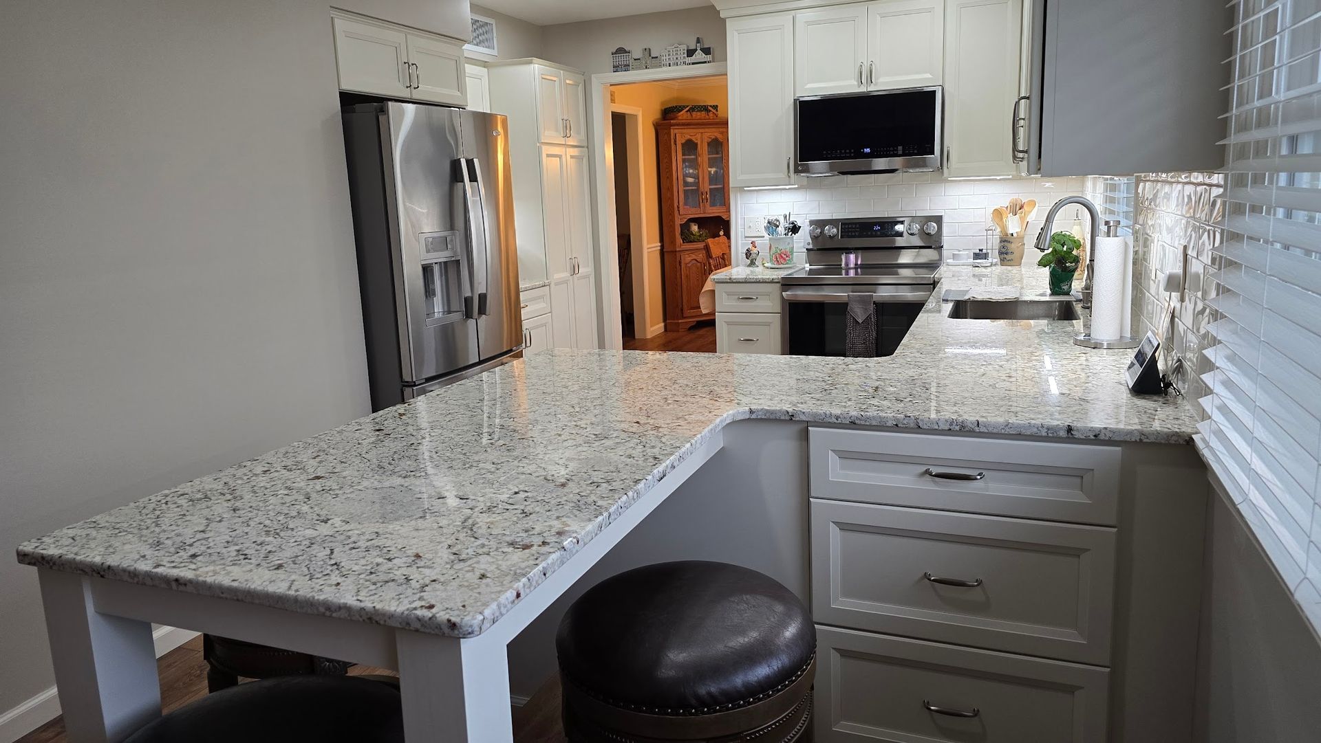 A kitchen with granite counter tops and white cabinets.
