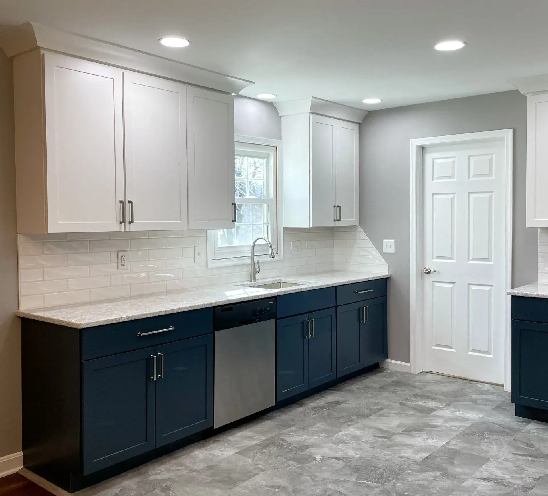 A kitchen with blue cabinets and white cabinets and a stainless steel dishwasher.