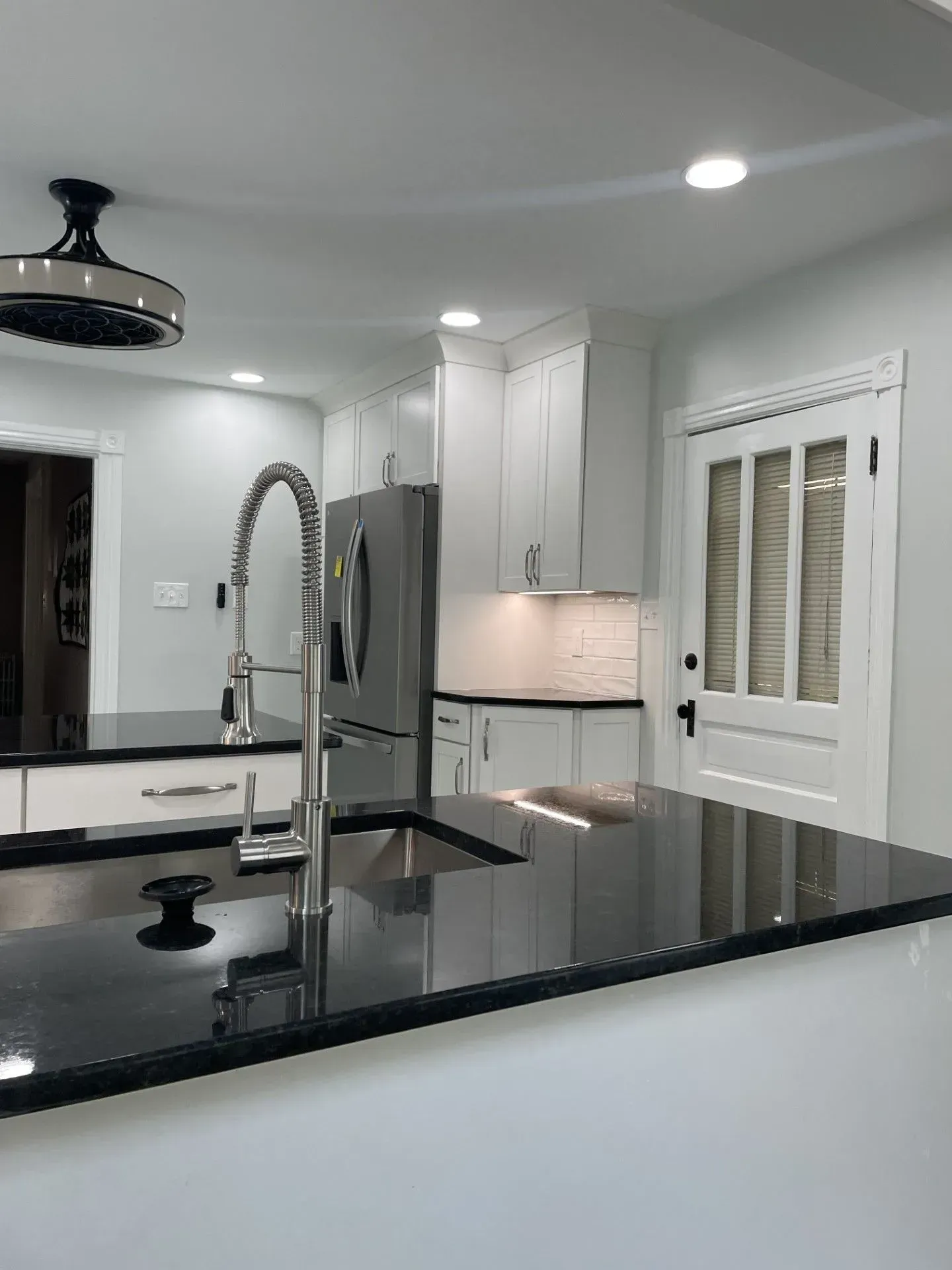 A kitchen with a sink , refrigerator , and a ceiling fan.