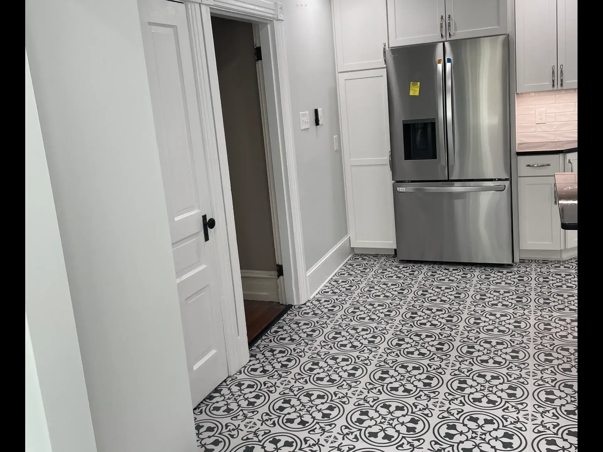 A kitchen with stainless steel appliances and a black and white tile floor.