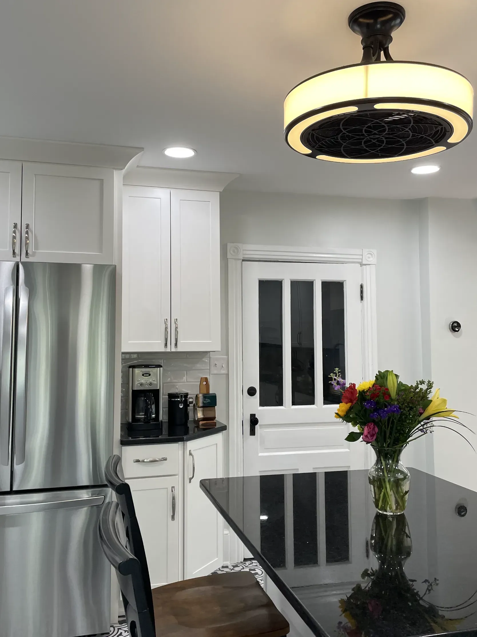 A kitchen with a stainless steel refrigerator and a vase of flowers on the counter.