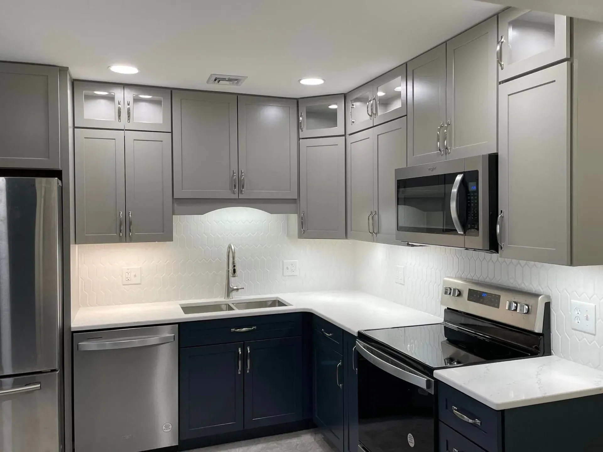 A kitchen with stainless steel appliances and gray cabinets.