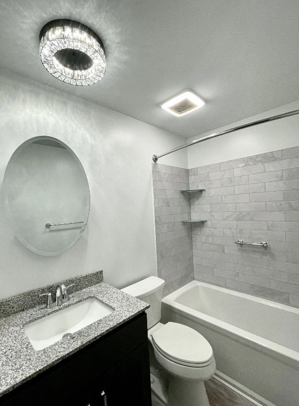 A bathroom with a toilet , sink , bathtub and mirror.