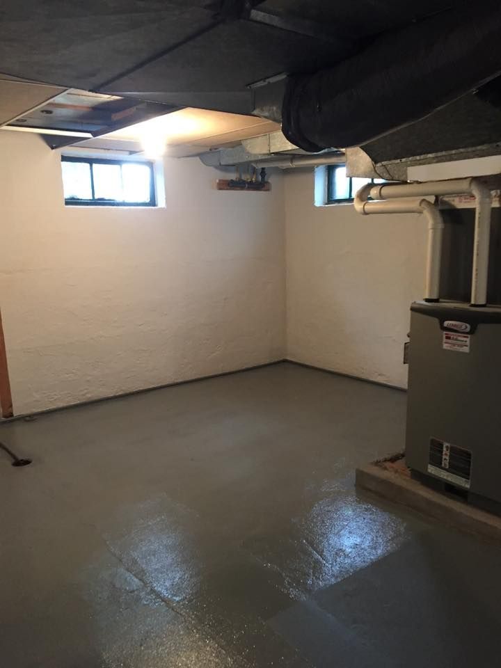 An empty basement with a furnace and a window.