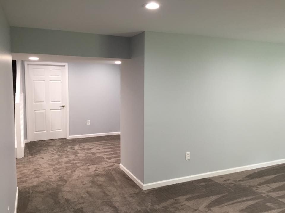 An empty basement with a carpeted floor and white walls.