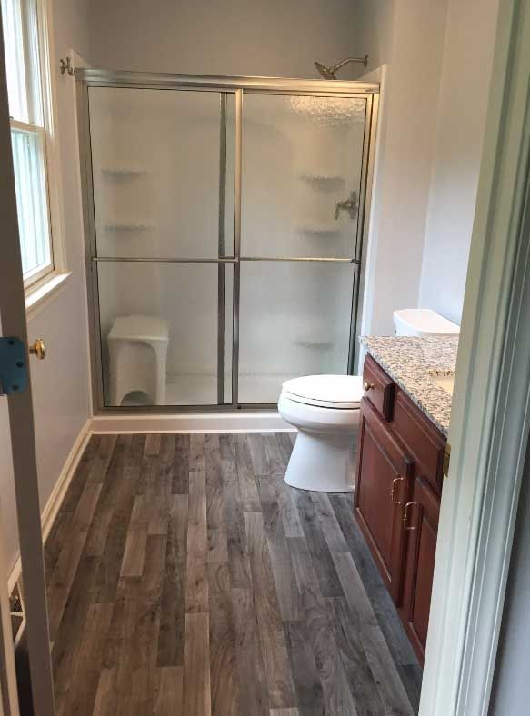 A bathroom with a toilet , sink and shower stall.