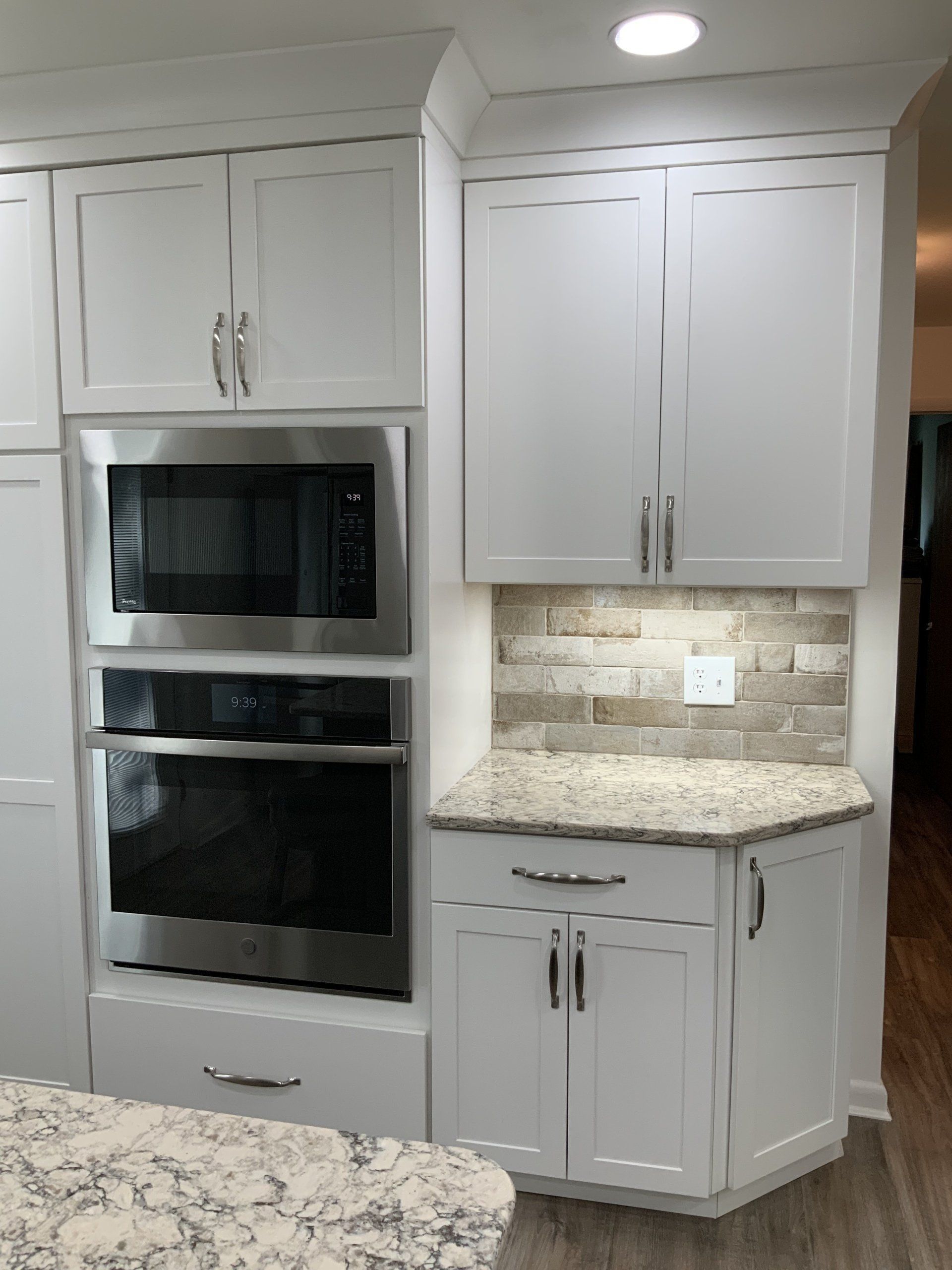 A kitchen with white cabinets and a microwave oven