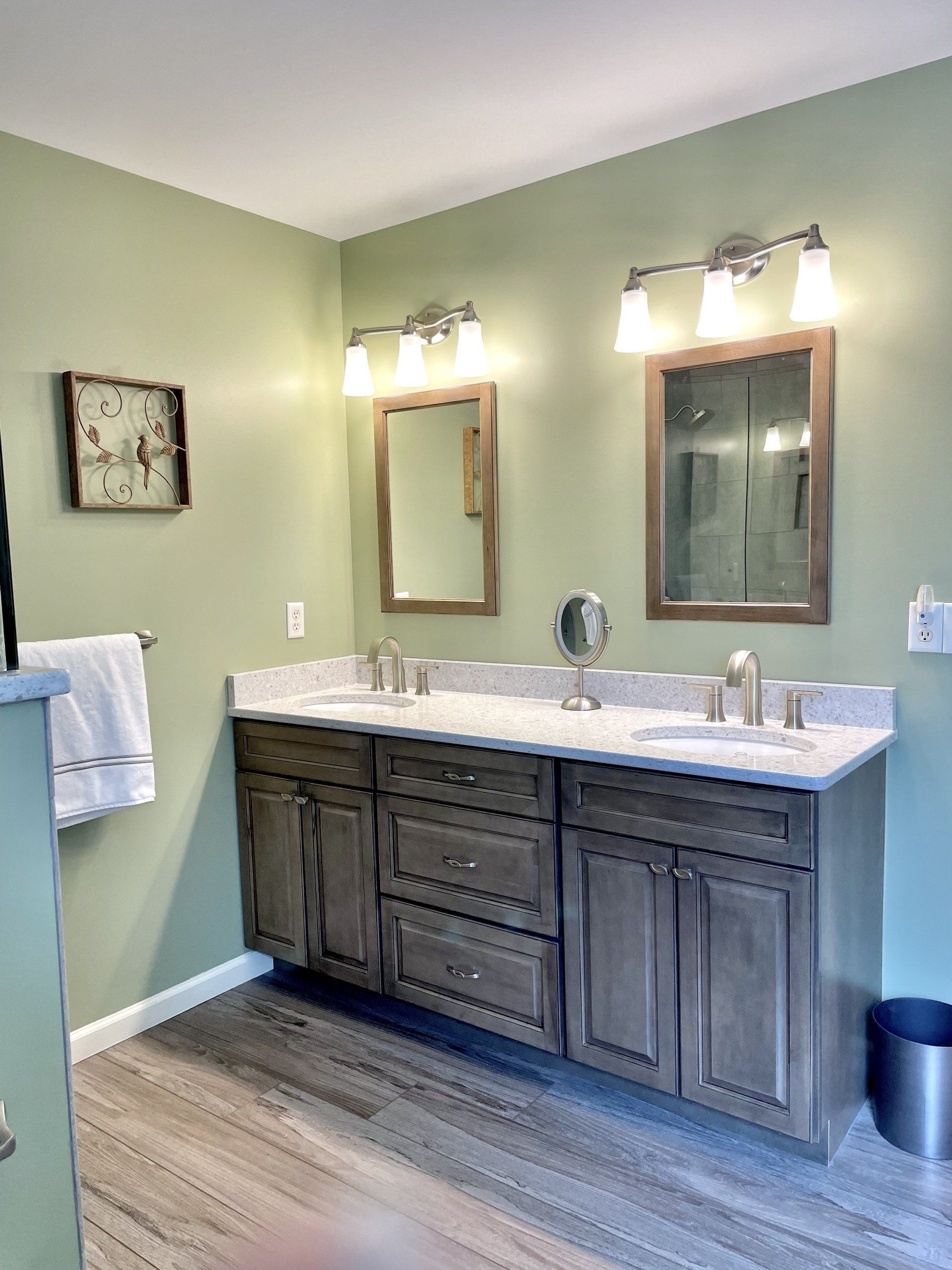 A bathroom with two sinks , two mirrors and a clock on the wall.