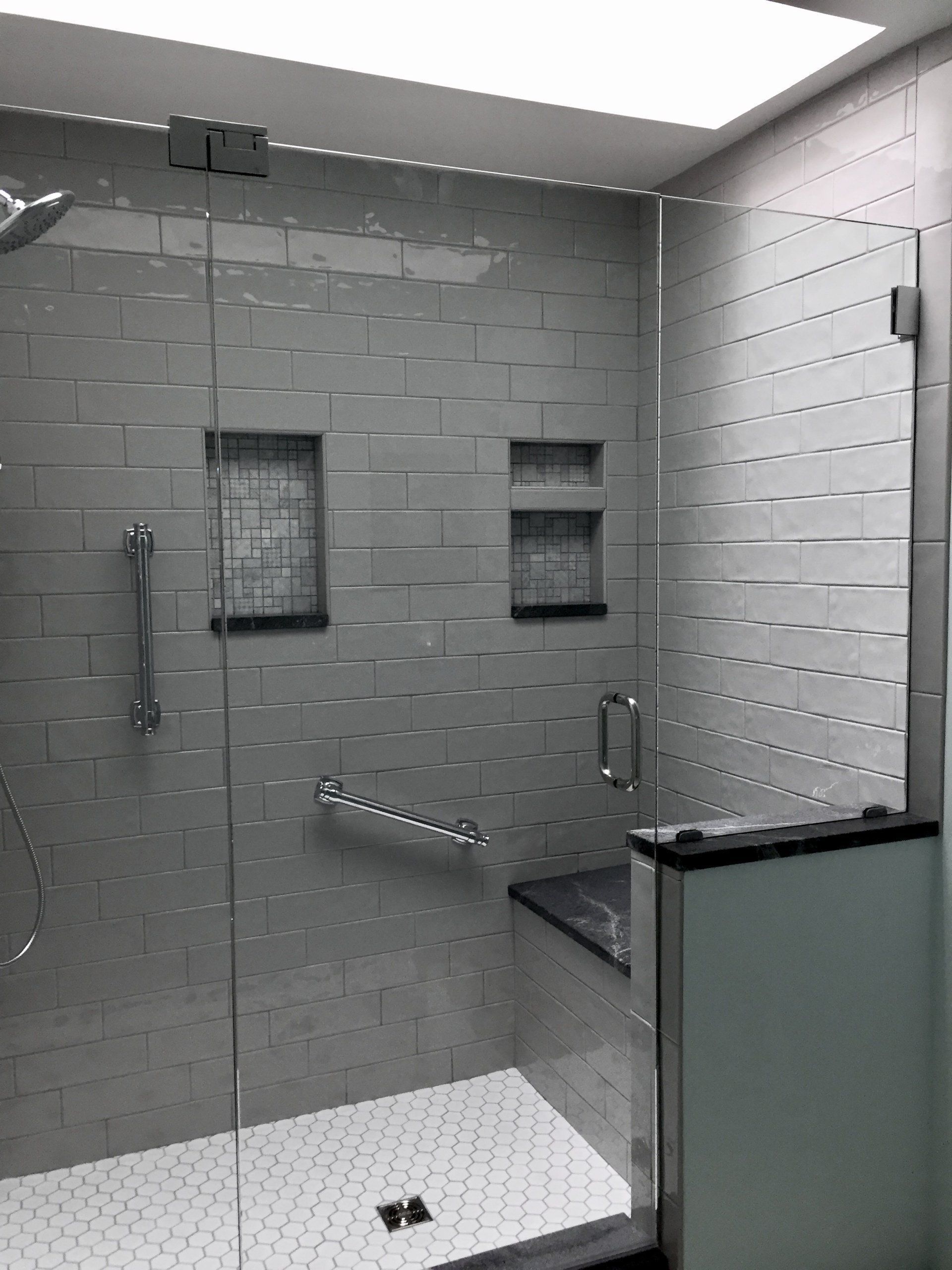 A bathroom with a walk in shower with a glass door