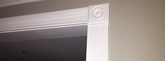 A close up of a white door trim on a wall.