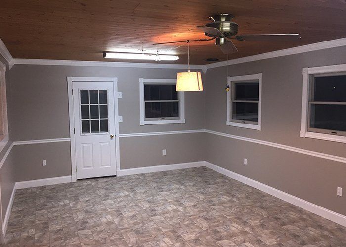 An empty living room with a ceiling fan and a door.