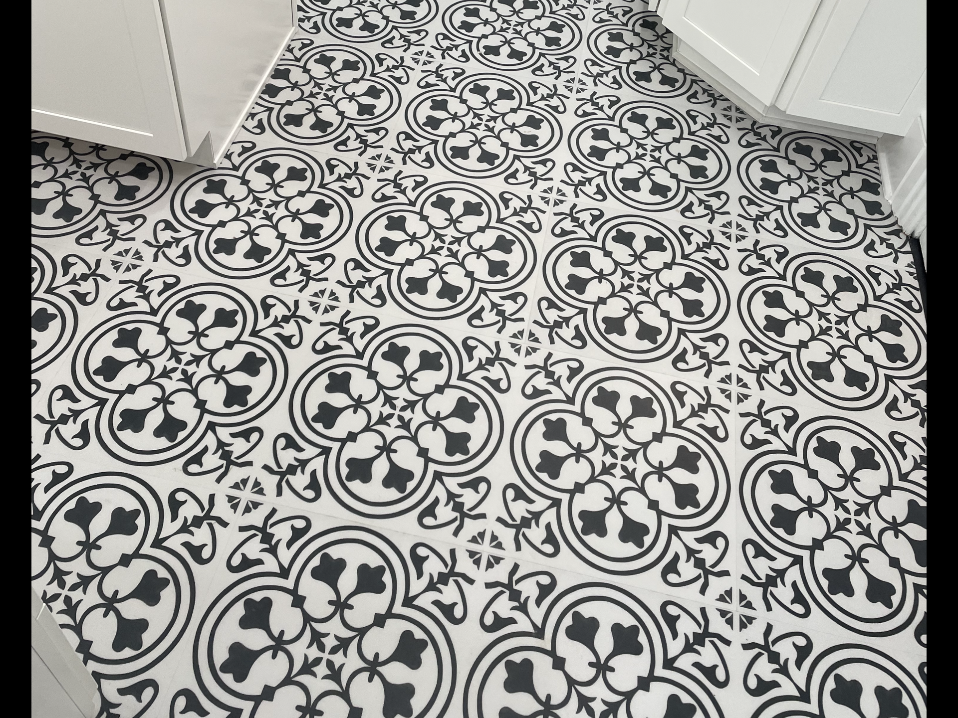 A black and white tile floor with a floral pattern.