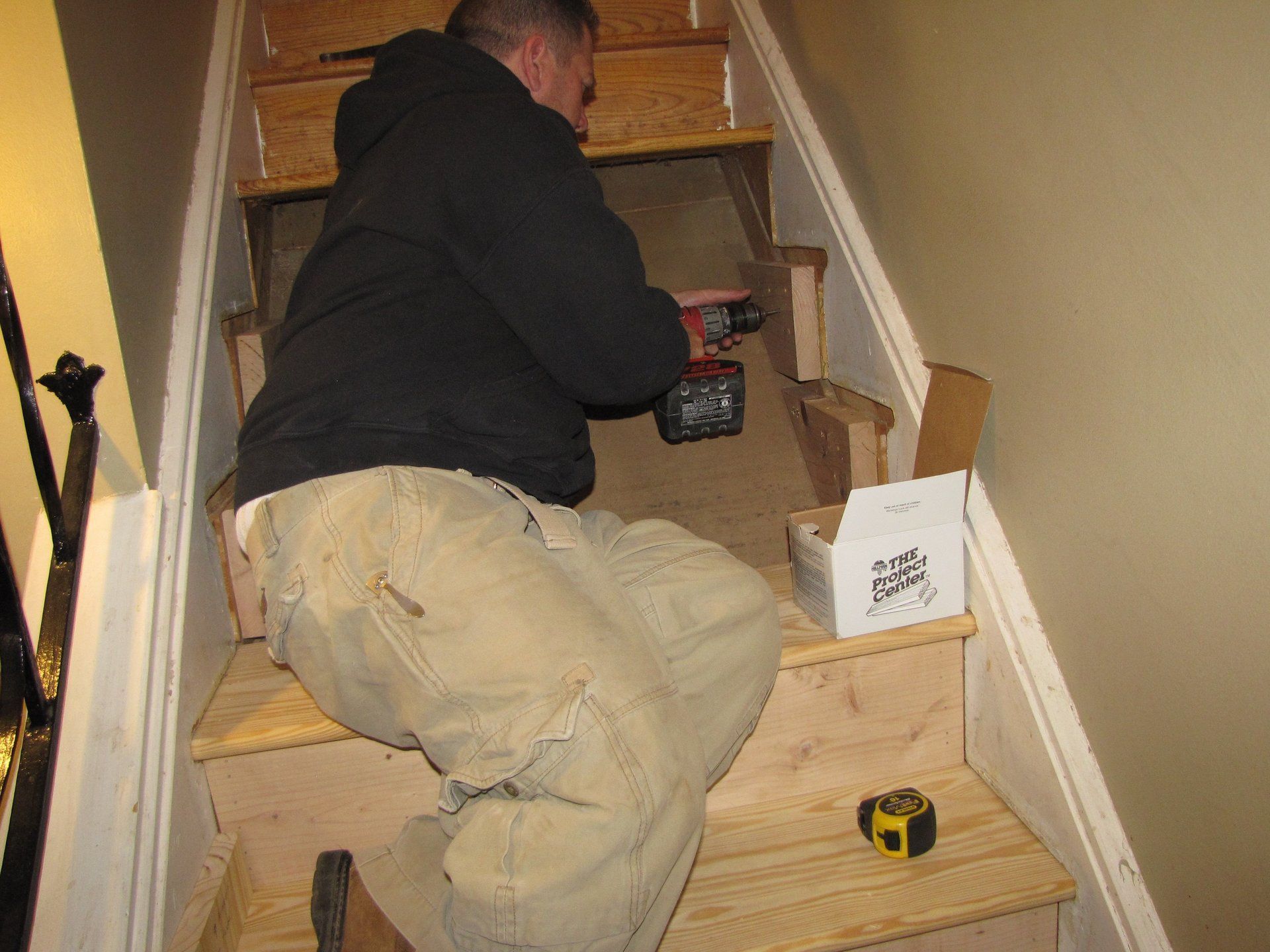 A man is working on a set of stairs with a drill