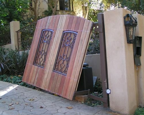 Partially open wooden gate leaning against a wall at a garden entrance