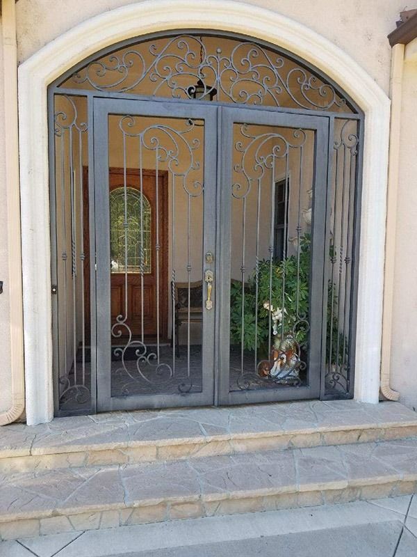 Decorative metal double doors with glass panels at a building entrance