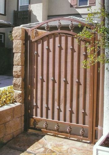 Brown wooden gate with metal spikes between stone posts in a courtyard entrance