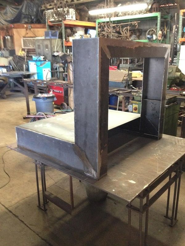 Metal workshop bench with a large rectangular steel frame on a table in a cluttered industrial shop.