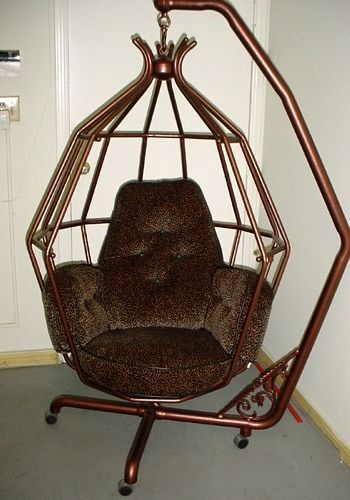 Brown hanging egg chair with cushioned seat on a metal stand in a room