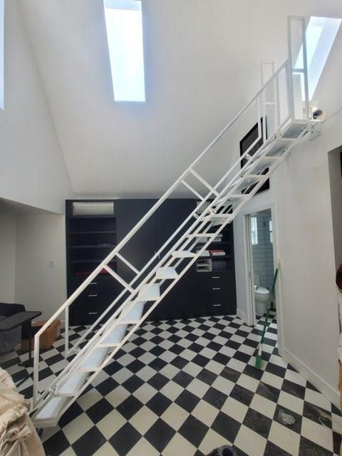 Bright stairway in a white room with black-and-white checkered floor and large windows