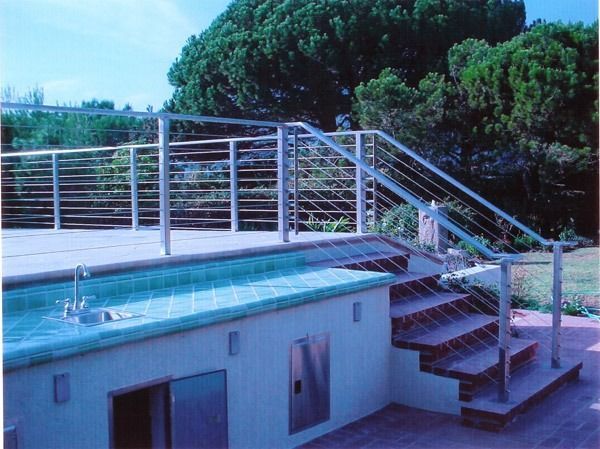 Outdoor swimming pool with metal railing and stairs beside a hillside