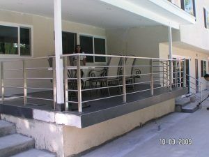 Covered apartment walkway with metal railing and steps leading to a raised patio.