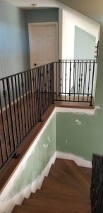 Interior staircase with black railing, green walls, and a closed door at the landing