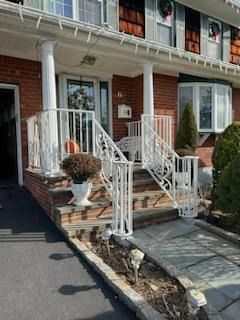 Brick townhouse entrance with white railings, front steps, and a small landscaped walkway
