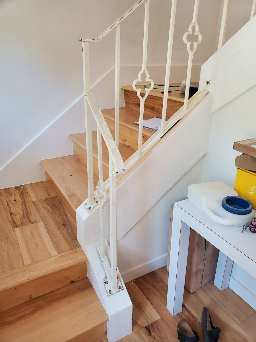 Staircase with wooden steps and white ornate railing beside a small white side table in a bright hallway